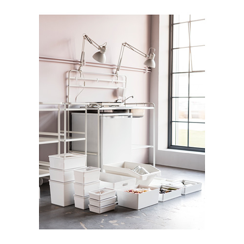 Minicocina SUNNERSTA en color blanco con estantes de acero inoxidable, lámparas ajustables, cajas y contenedores ordenados en el suelo.