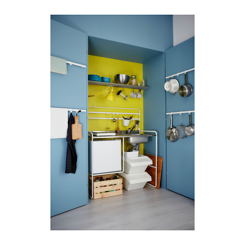 Cocina luminosa con paredes azules, placa para salpicaduras amarilla, ollas colgantes, taburete de madera, fregadero y unidades de almacenamiento.