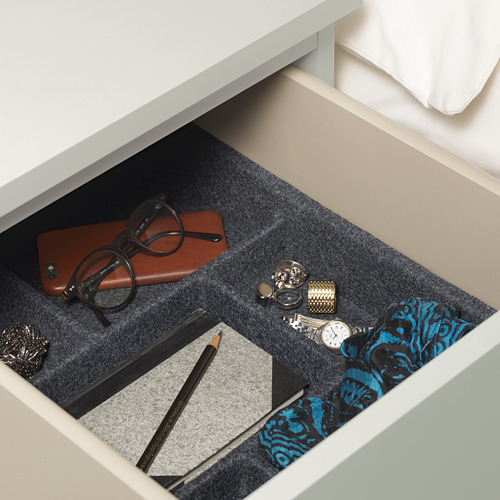 Cajón abierto con bandejas de fieltro para guardar gafas, cartera, reloj, bolígrafo y bufanda.