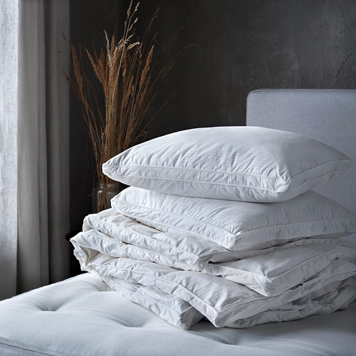 Una pila de cuatro edredones nórdicos fjällräven blancos sobre una cama, con lados cosidos, que brindan un aspecto cálido y acogedor.
