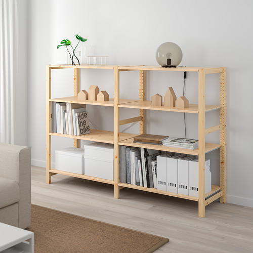 La estantería delgada de madera clara cabe perfectamente en la habitación, sosteniendo libros, cajas y decoración.