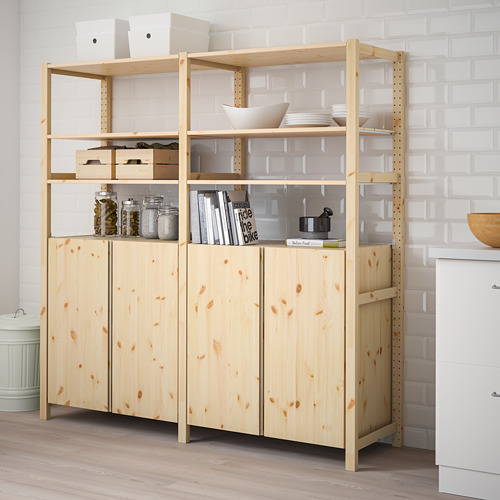 Mueble de almacenamiento IVAR de madera con estantes y artículos, junto a la pared de ladrillo blanco.