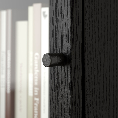 Primer plano de un moderno tirador cilíndrico negro sobre un cajón de madera oscura; Elegante y con estilo.