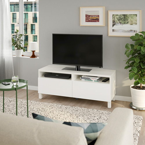 Sala de estar moderna con mueble de TV BESTÅ, planta, silla y vista a la ciudad.