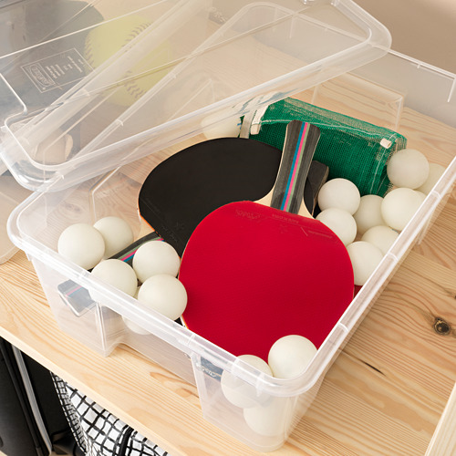 La caja de almacenamiento de plástico transparente contiene el equipo de ping pong, con la tapa abierta.