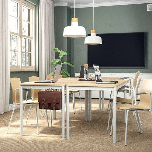 Moderna configuración de oficina con mesa de madera, sillas, computadora portátil, planta, 2 lámparas colgantes, TV y ventana.