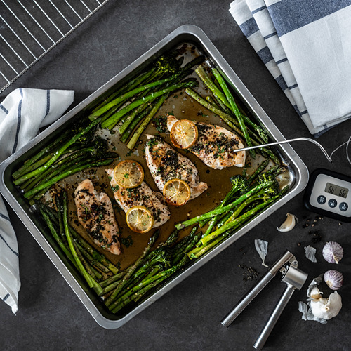 Asador rectangular de acero inoxidable con pollo a la parrilla, espárragos y limón.