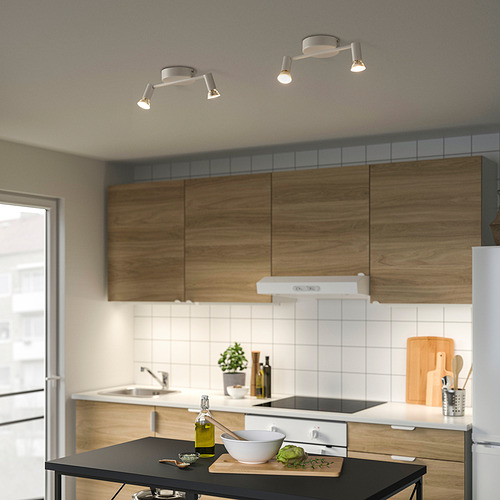 Cocina moderna con luces de riel en el techo sobre la isla, con focos ajustables y gabinetes de madera.