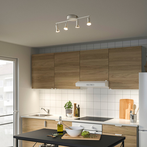 Cocina moderna con plafones, armarios de madera, electrodomésticos de acero, isla negra con tazón, tabla de cortar y aceite de oliva.
