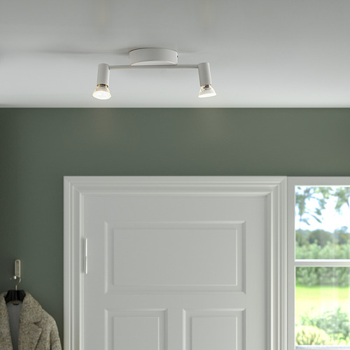 Plafón blanco con dos focos orientables, que iluminan una pared verde y una puerta blanca.