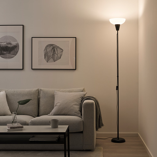 Una sala de estar con un sofá gris claro, una lámpara de pie negra más alta que otros elementos, una mesa de centro y arte en la pared.