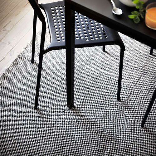 Silla moderna negra sobre alfombra gris con un sutil estampado.