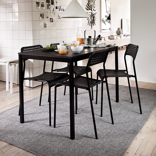 Cocina moderna con juego de comedor negro, comida, placa para salpicaduras blanca, alfombra gris.