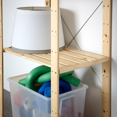 Estantería de almacenamiento de madera con una pantalla de lámpara blanca en el estante superior y un contenedor transparente de flotadores de piscina en el estante inferior.