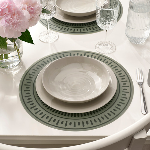 Elegante mesa con manteles individuales, vajilla, vasos, flores y utensilios verdes y blancos.