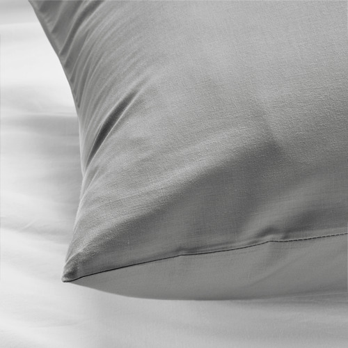 Un primer plano de una almohada gris suave y acogedora sobre una cama, que muestra su textura de algodón suave y duradera.