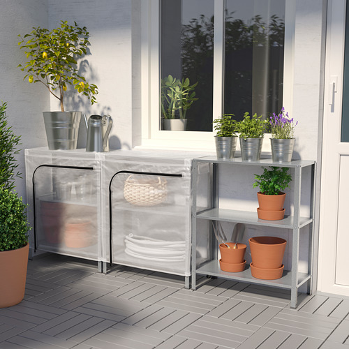 Moderno soporte para plantas de metal gris con cubierta de invernadero. Sostiene varias plantas en macetas y herramientas. Perfecto para interiores o exteriores.