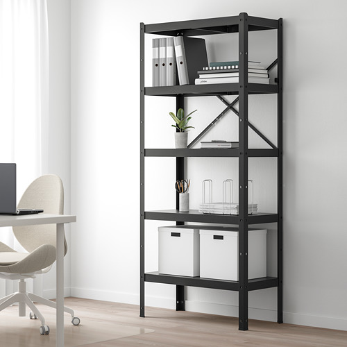 Estantería BROR negra en la oficina, llena de libros, plantas y contenedores. Acero robusto, versátil, más alto que una silla.