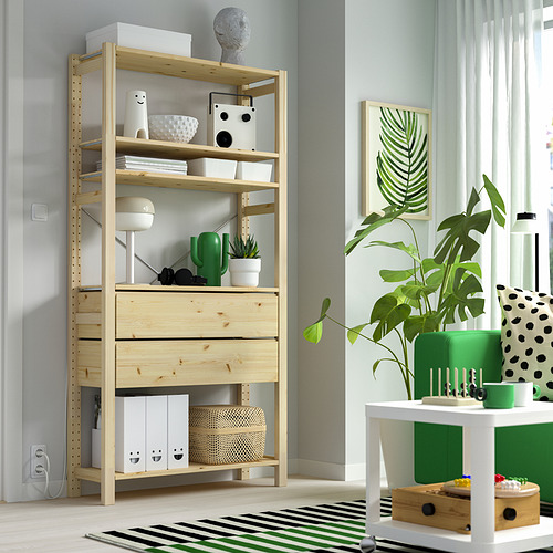Habitación moderna con mueble de almacenamiento y decoración de pino IVAR. Mueble alto junto a una gran planta de interior sobre una mesa blanca.