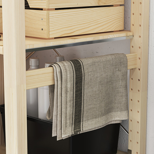 Estantería de madera con estantes móviles; De uno cuelga una tela gris.