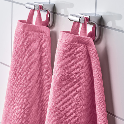 Dos toallas VÅGSJÖN rosas cuelgan de ganchos metálicos, con una textura suave y absorbente, listas para usar.