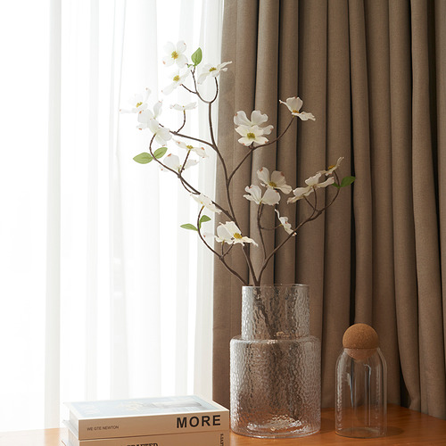 Jarrón de vidrio con flores, libros, jarra sobre mesa de madera, cortinas marrones