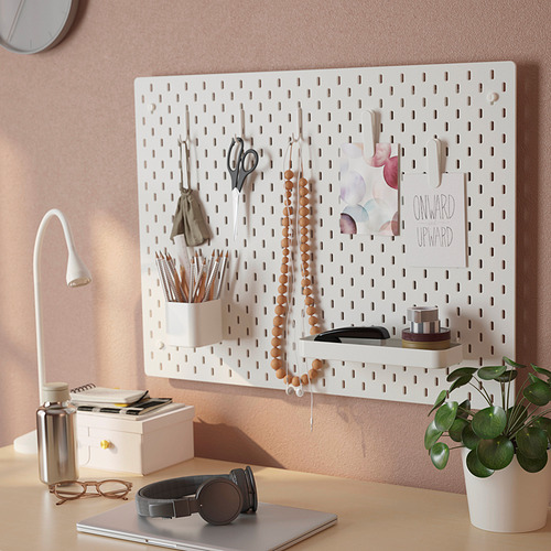 El tablero perforado SKÅDIS blanco organiza el material de oficina, la decoración y cuelga los artículos de manera eficiente.