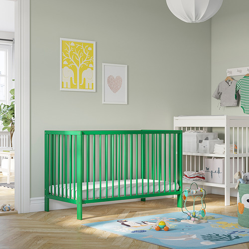 Cuna GULLIVER verde brillante, diseño moderno. Base ajustable, lateral desmontable y marco de madera maciza. Encaja bien en una habitación infantil espaciosa con decoración pastel.
