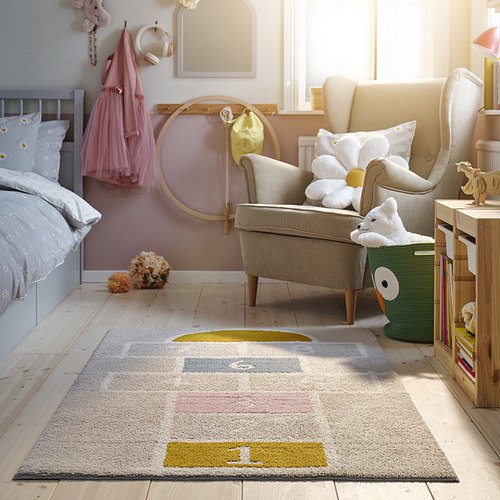 Alfombra STÄPPSPARV, gris, rectangular, suave, cabe debajo de la silla, con libros cerca.