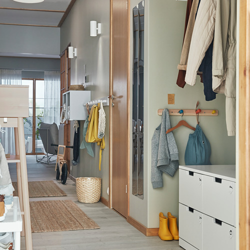 Pasillo organizado con lámparas NYMÅNE, gancho para ropa, botas amarillas, planta y cesta.