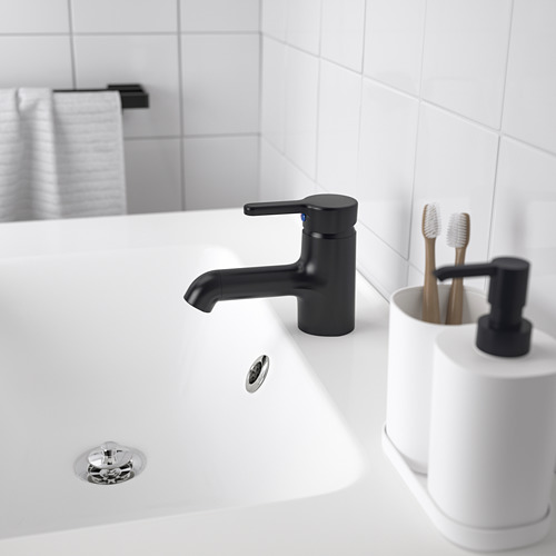 Un lavabo de baño moderno con un elegante grifo SALJEN negro, encimera blanca y un soporte para cepillos de dientes.