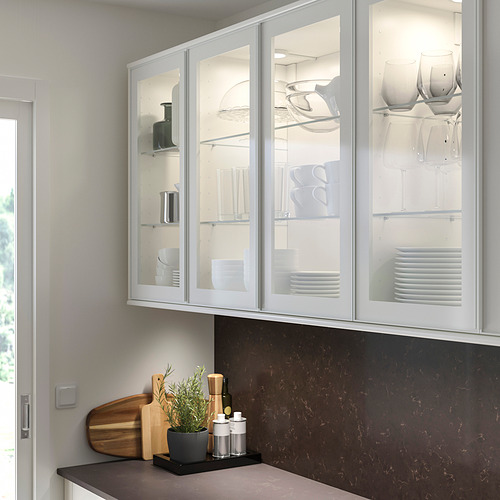 Cocina moderna con gabinetes altos de vidrio blanco HEJSTA, elegantes manijas de aluminio y encimera oscura que exhibe utensilios de cocina.