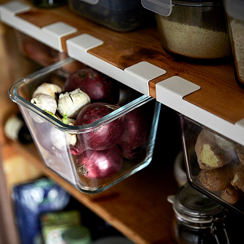 El contenedor de vidrio que almacena remolacha y ajo, que forma parte de IKEA 365+, organiza los artículos de cocina de forma ordenada.