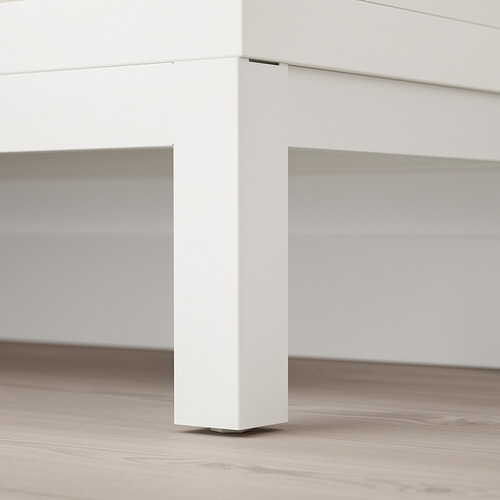 Pata minimalista de metal blanco sobre suelo de madera, que soporta un elegante escritorio.
