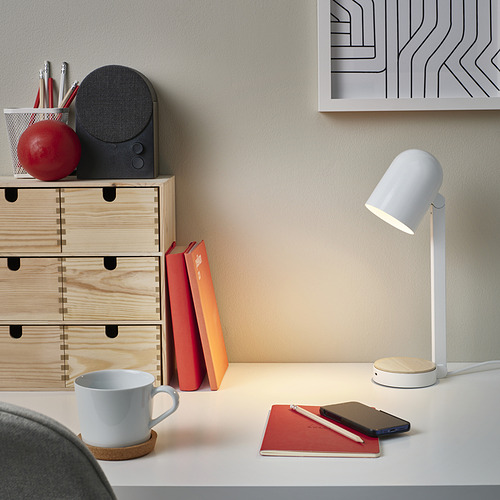 Montaje de escritorio con lámpara blanca ENSMÄRKE, pequeño, moderno y eficiente. Cajones de madera, libros y una taza completan el look organizado.