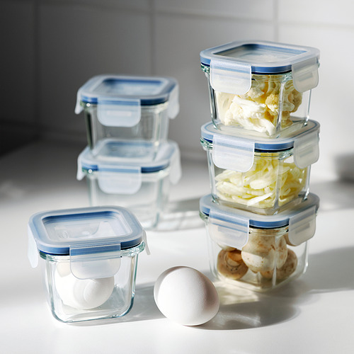 Los recipientes de vidrio apilados para alimentos con tapas azules almacenan los alimentos, evitan derrames y permiten la visibilidad del contenido.