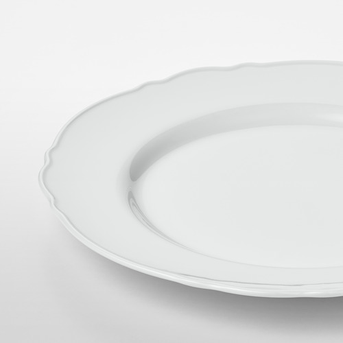 Elegante plato de porcelana blanca pura con delicado borde con volantes. Superficie lisa de alta calidad. Lavaplatos.