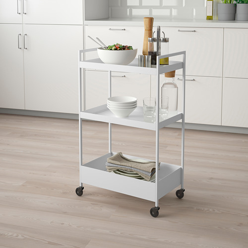 Carro metálico NISSAFORS con 3 estantes en la cocina que contienen ensalada, platos, vasos y toallas.