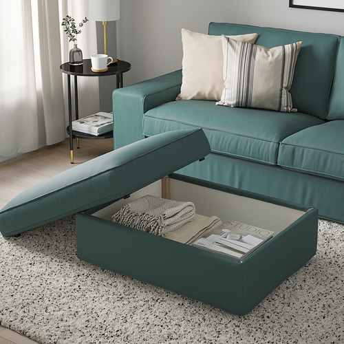 Reposapiés KIVIK verde con almacenamiento debajo del asiento, sobre alfombra moteada, combinado con sofá verde, dos mantas en el interior.