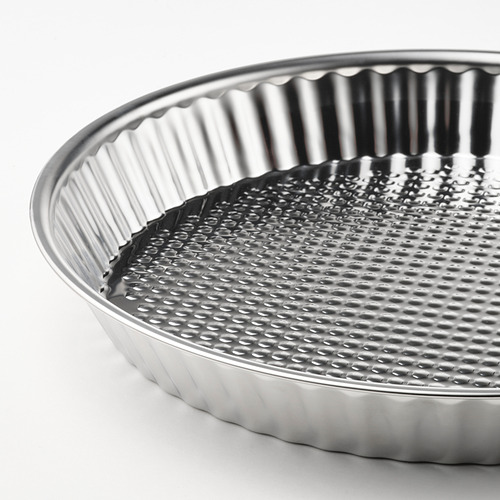 Primer plano en blanco y negro de un molde para hornear de acero inoxidable de alta calidad con un borde estriado y un fondo con hoyuelos.