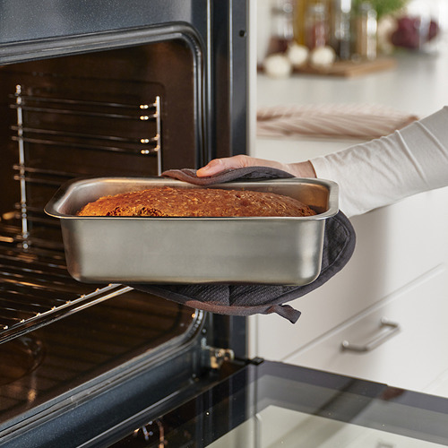 Una persona que usa un molde para hornear pan en un horno. El molde garantiza una distribución uniforme del calor para hornear en tonos marrones dorados.