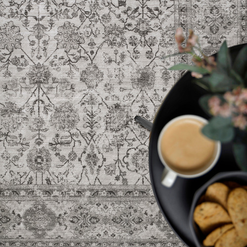 Thin, patterned rug, likely made of recycled polyester. Coffee cup and cookies placed on it.
