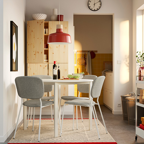 Pequeño y moderno juego de comedor con mesa blanca y sillas grises. Luminosa vista a la cocina.