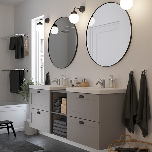 Baño moderno con grandes espejos redondos lindby, marcos oscuros, tocador y apliques. Decorado con toallas, plantas y cestas.