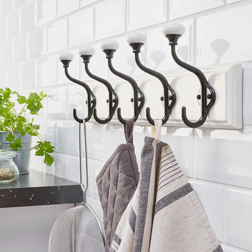 Estante de pared negro con cinco ganchos dobles que sujetan toallas, que ofrece un amplio espacio para colgar en la cocina.