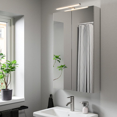 Baño moderno con lámpara VÅTHULT sobre el lavabo, espejo y planta.