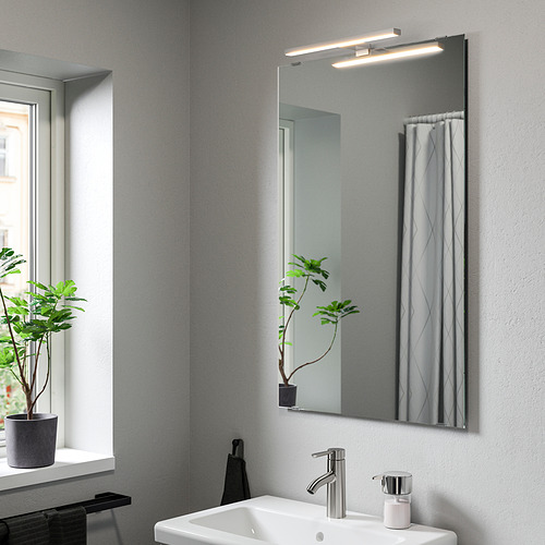 Baño moderno con lámpara de pared VÅTHULT, diseño elegante, encima del lavabo.