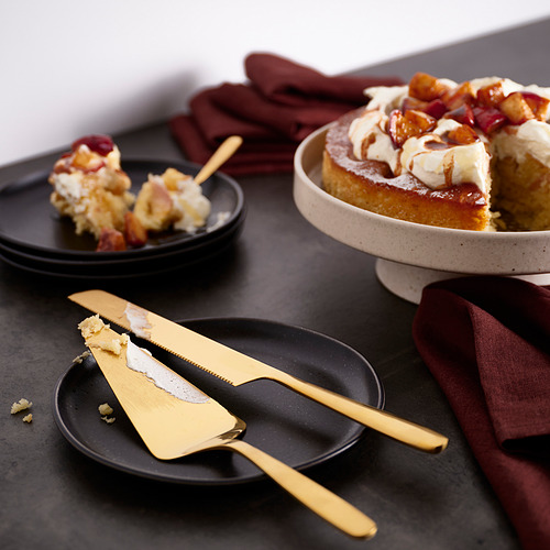 Rebanada de pastel dorado TILLAGD y cuchillo en la mesa, con postre parcialmente cortado. Cortar en rodajas grandes, descansando en un plato oscuro, largo como un cuchillo.