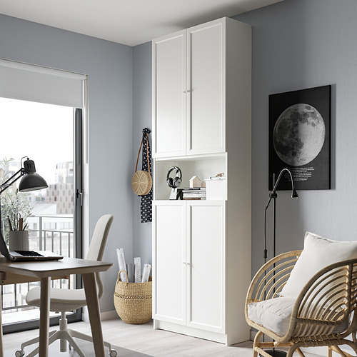 Moderna oficina en casa con estantería BILLY, escritorio, silla de mimbre, luz natural, portátil y decoración.
