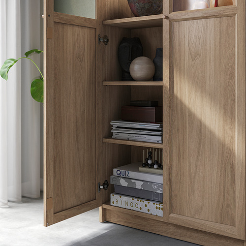 Estantería de madera con puertas de vidrio que muestra estantes llenos de libros, artículos de decoración y juegos, lo que demuestra capacidades versátiles de almacenamiento y exhibición.